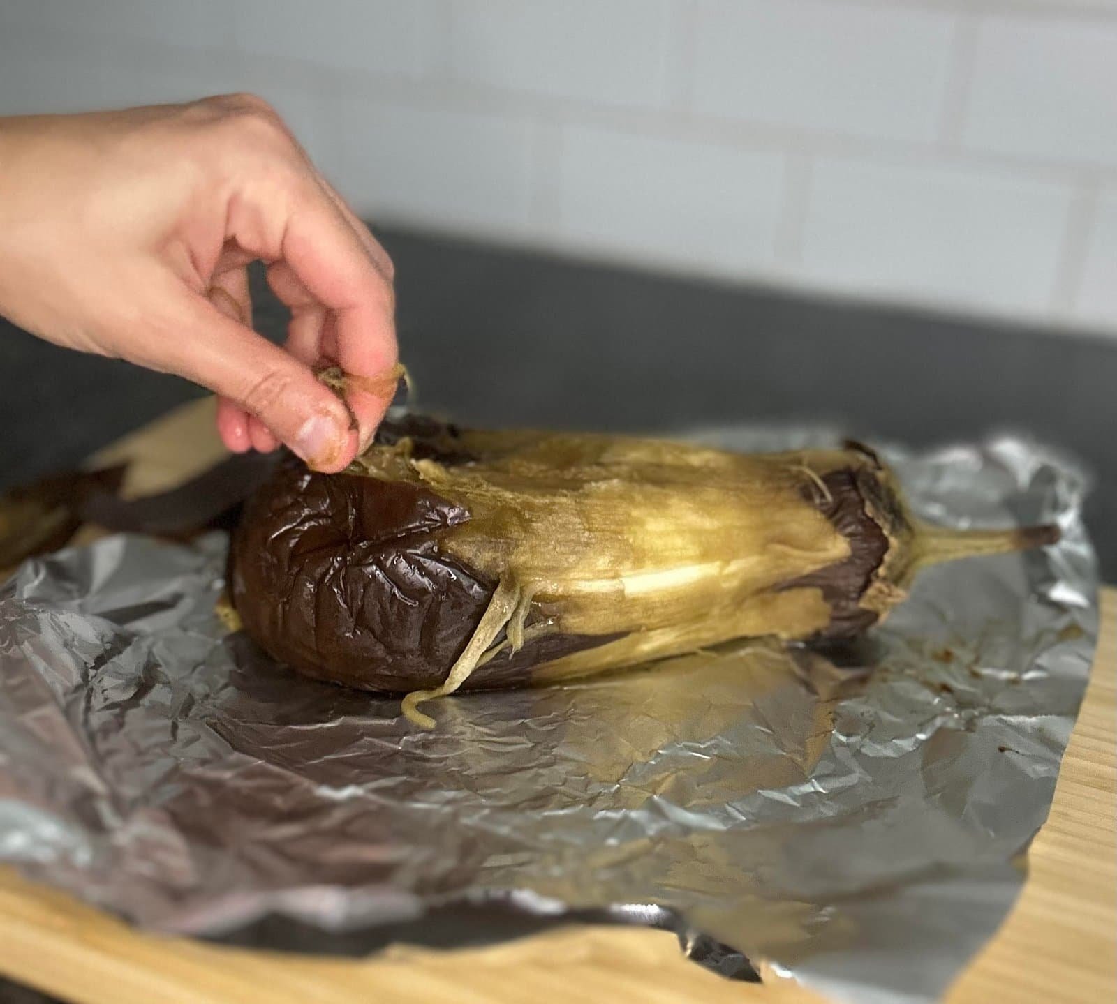 Eggplant a hand peeling a eggplant on foil